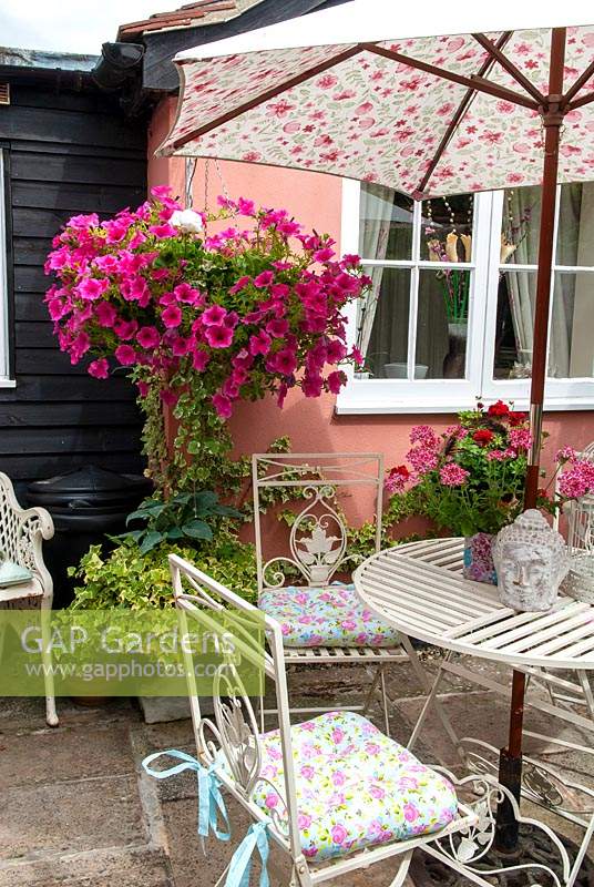 Floral sunshade over table and chairs with pot of Verbenas on table and hanging basket of  Petunias - Open Gardens Day, Woolpit, Suffolk