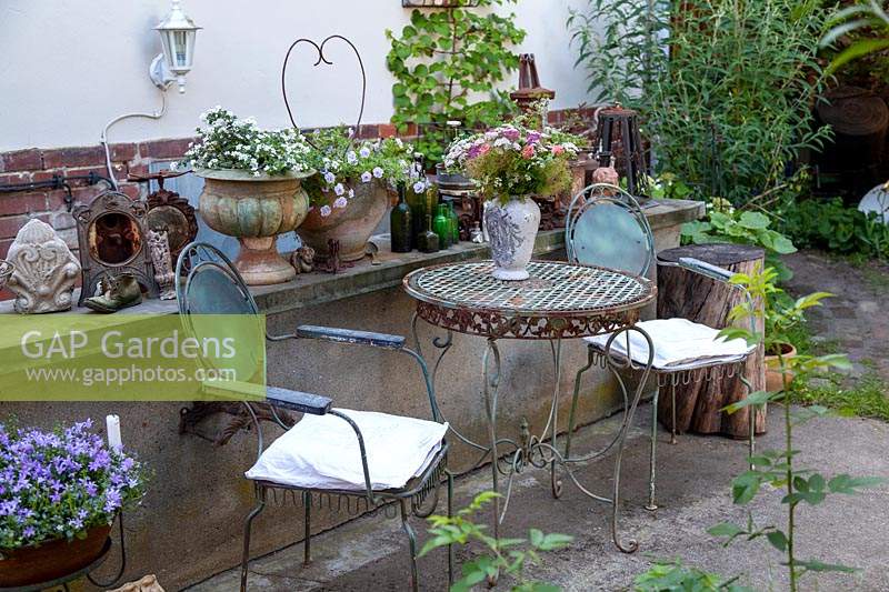 Old garden furniture in courtyard with collection of pots