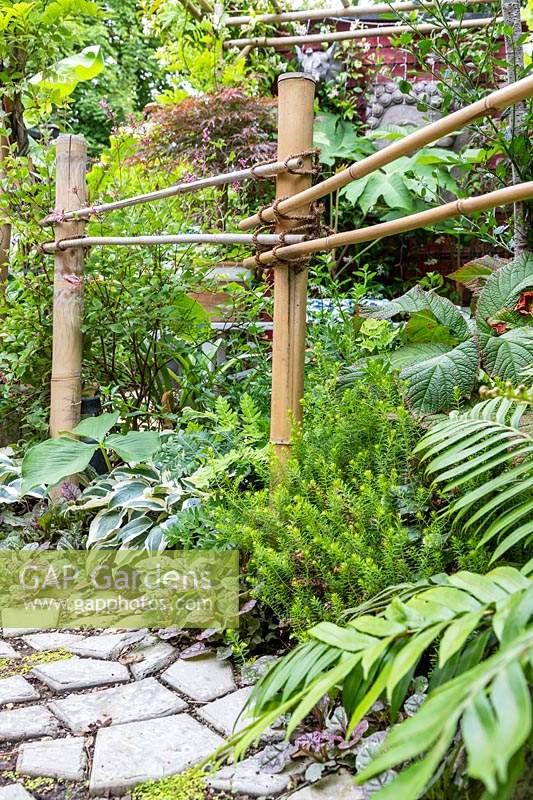 Simple bamboo fencing along edge of path with mixed planting