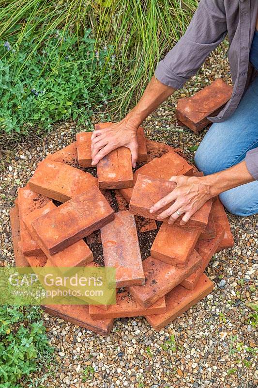 Woman adding more bricks to centre of tower to create the top