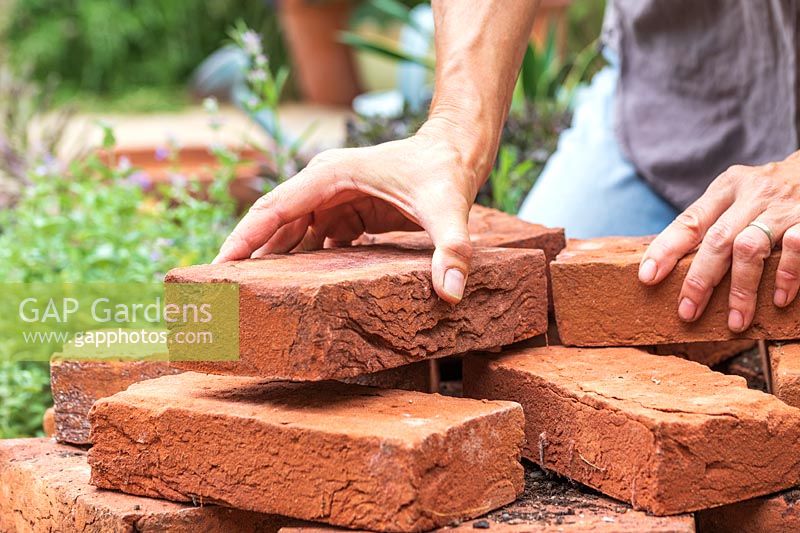 Woman adding more bricks to centre of tower to create the top