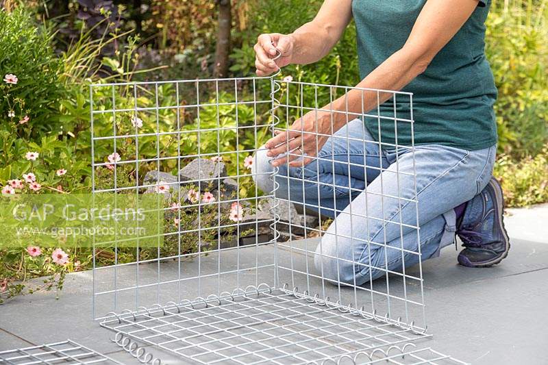 Woman using spiral helicoils to join components of gabion basket