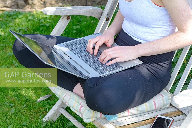 Young girl using a laptop while working and studying from home in the garden.  