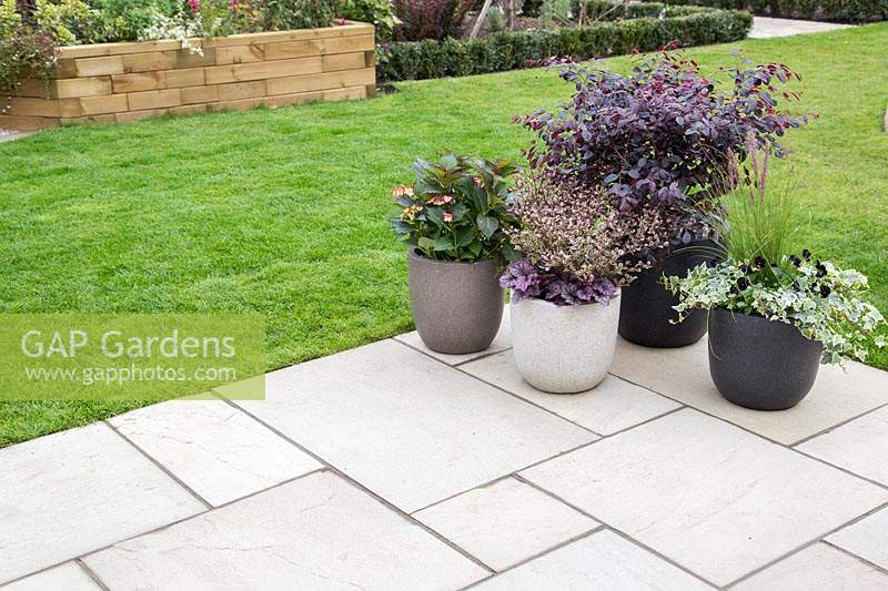 Patio with mixed slabs and group of containers. 