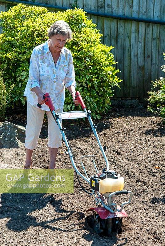 Woman using Mantis tiller on area of border to be replanted
