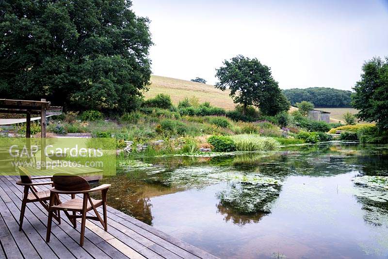 Timber decking brings the house into close contact with the large pond that occupies the site of a former intensive pig unit at Am Brook Meadow, Devon in August. 