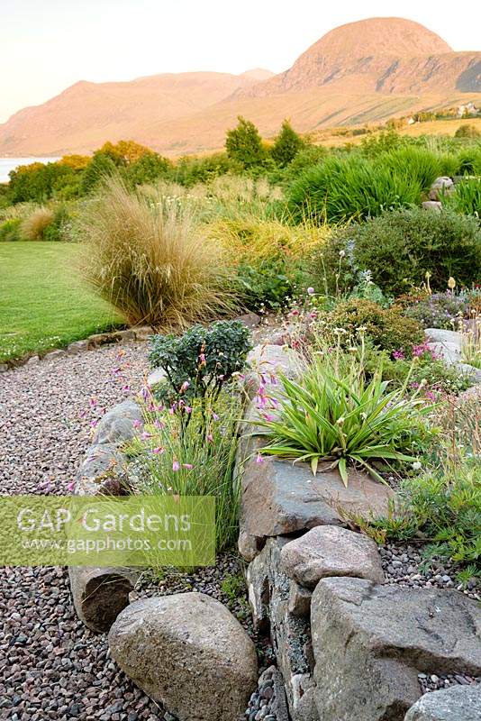 Terraced borders in Scottish garden, with mixed planting and view of Sail Mhor beyond. 
