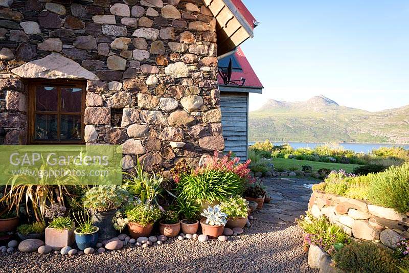 A collection of pots and containers in private garden on Little Loch Broom, Wester Ross, Scotland, with the distinctive shape of Beinn Ghobhlach beyond.