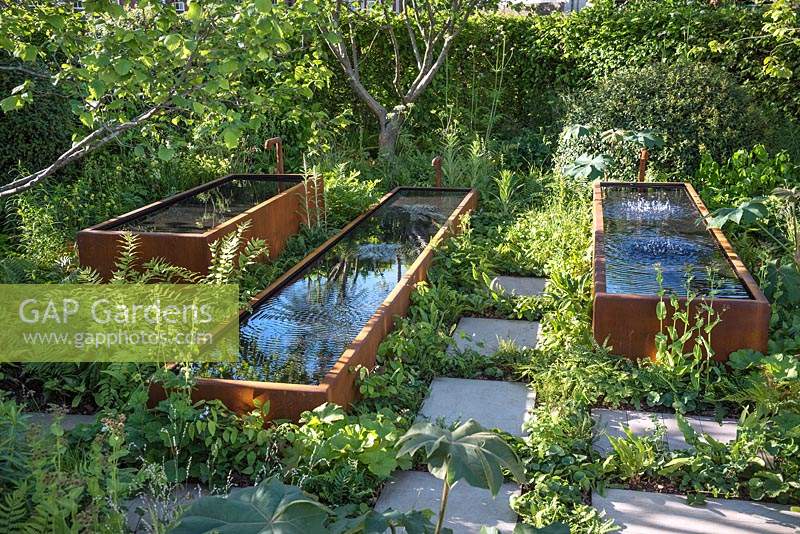 Rusted steel water troughs whose surface ripples when music from Radio 2 is played through the gravel below, shade tolerant planting includes: Tetrapanax, ferns and small flowering perennials. The Zoe Ball Listening Garden, built by Crocus