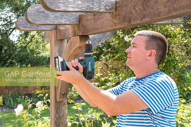 Man using an electril drill to predrill a fine hole in timber 