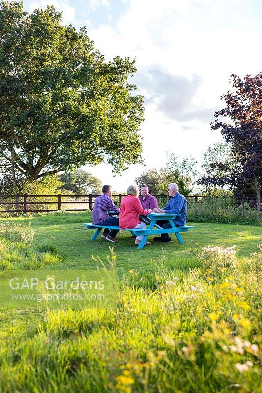 People sitting at newly assembled picnic bench in meadow