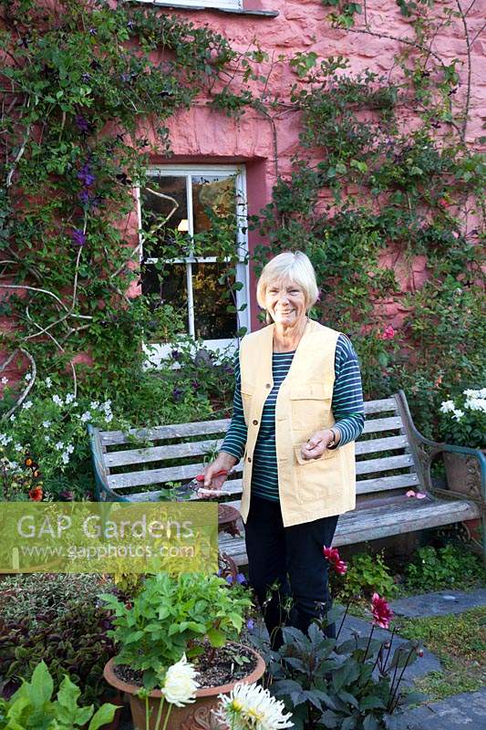Garden Owner Christina Shand standing in front of her pink cottage, Wales