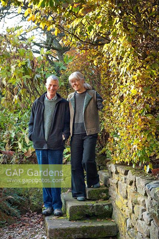 Couple standing on steps by hedge in a garden