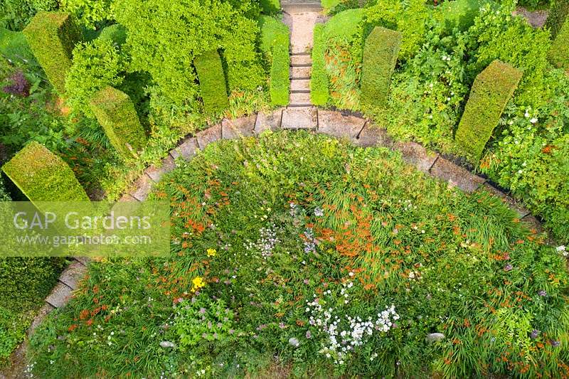 View of the Wild Garden with steps in gravel. Columns of Taxus baccata. Image taken from drone. The garden has been created since 1987 by garden writer Anne Wareham and her husband, photographer Charles Hawes.
