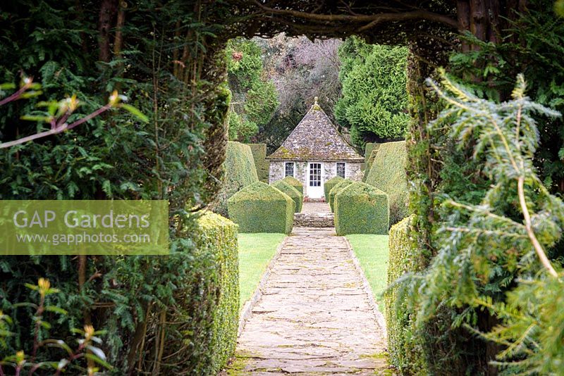 View towards the summerhouse, framed by an opening in a yew hedge at Rodmarton Manor, Glos, UK. 