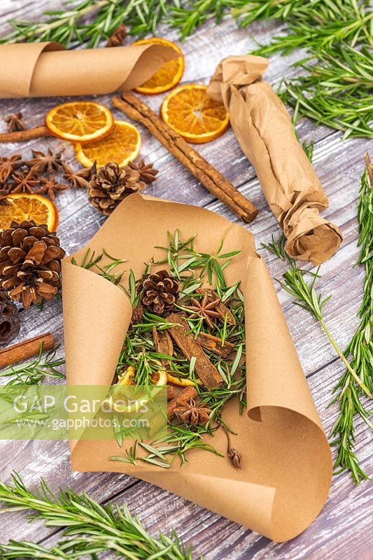 Scented fire starters made with Salvia rosmarinus syn. Rosmarinus - Rosemary - in brown paper with cinnamons sticks, orange slices, star anise and pine cones