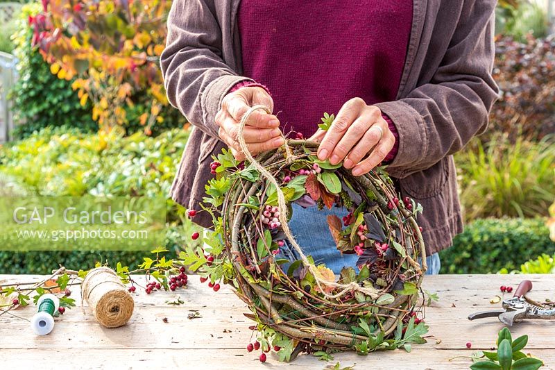 Woman attaching string to back of a wreath form