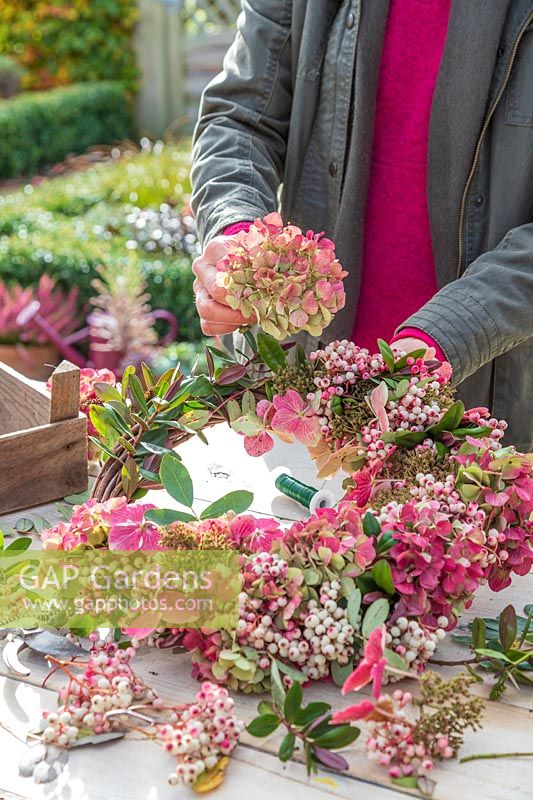 Woman adding dried Hydrangea flowerheads to the wreath