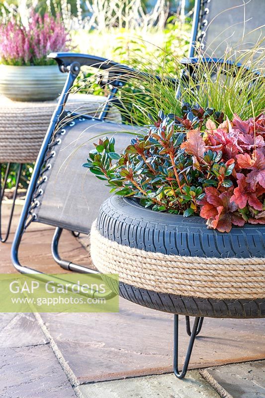 Decorative tyre planter on patio with reclining chair