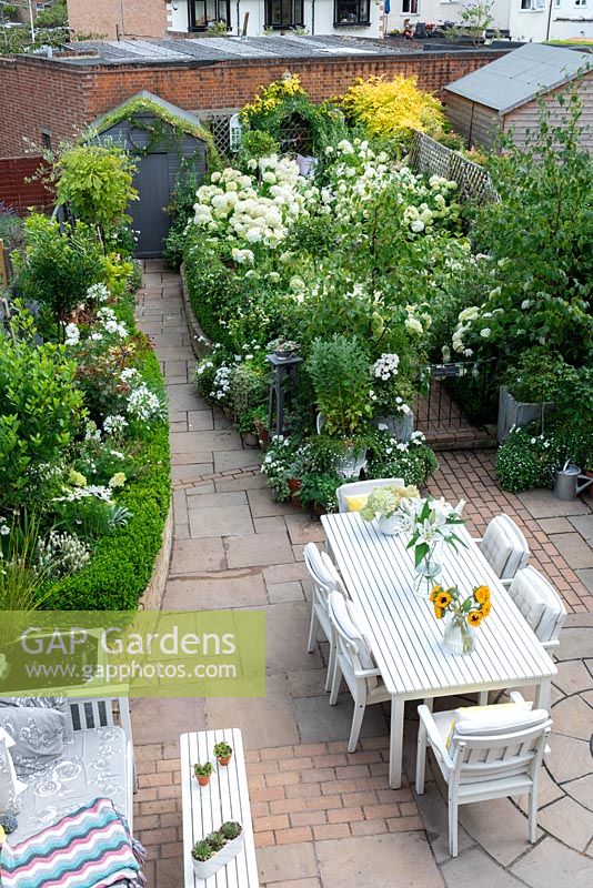 Bird's eye view of a small town garden, with dining and seating areas and white-themed borders.