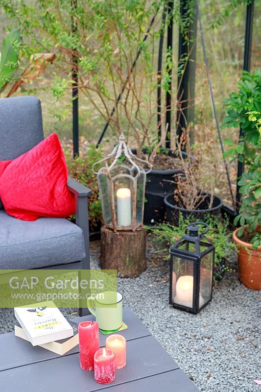 Large greenhouse with lounge furniture, cushions and lit candles in lanterns