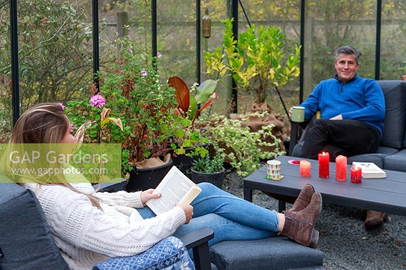 Father and daughter relaxing in lounge furniture in a greenhouse 