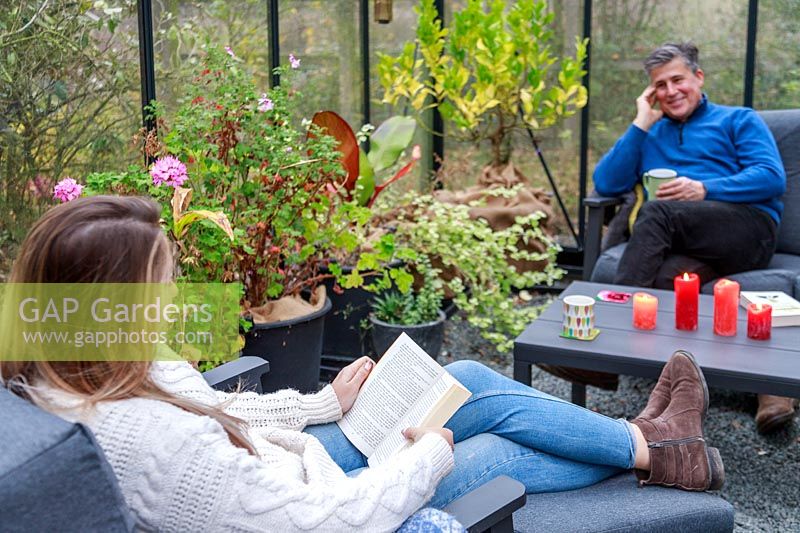 Father and daughter relaxing on lounge furniture in a greenhouse 