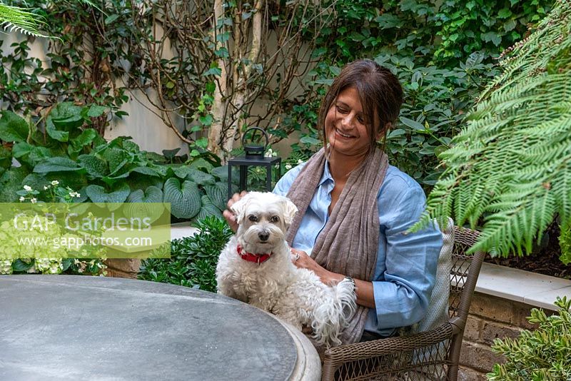Woman sitting in her small courtyard garden with a pet dog called Bailey