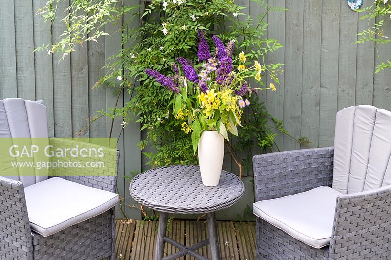 Armchairs and small table by fence painted in the same colour