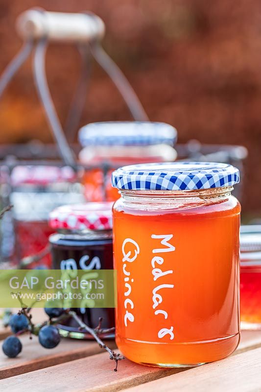 Glass jars with preserves on wooden table outside. 