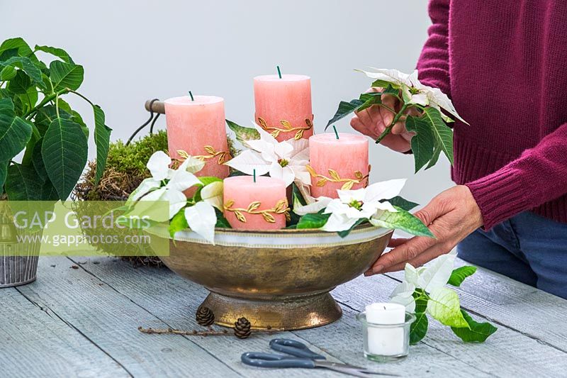 Woman adding cut and seared Poinsettia flowers to bowl arrangement