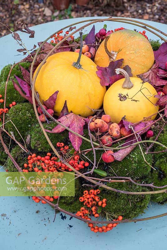 Moss wreath filled with small squash, berries, leaves and crab apples