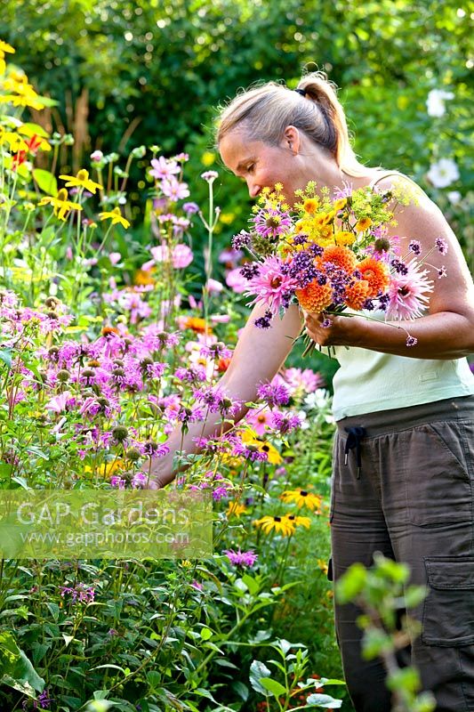 Woman is making floral arrangements from picked summer flowers.