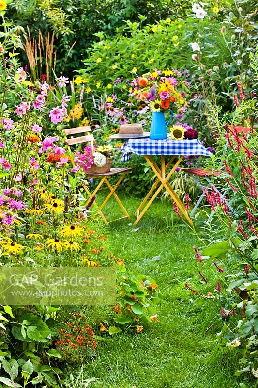 Table with flowers surrounded by flowering summer borders.