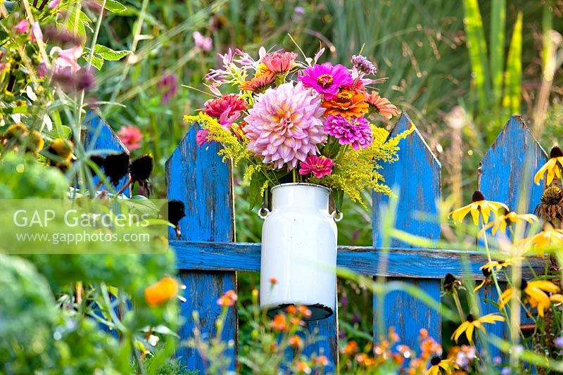 Flower bouquet in a milk can on a fence