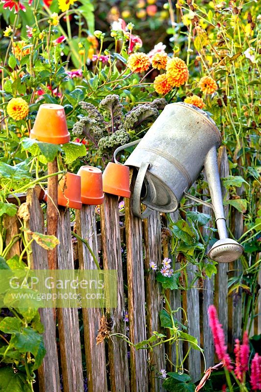 Watering can and terracotta pots on a fence.