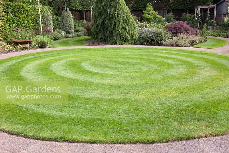 Curving gravel path around circular lawn. 