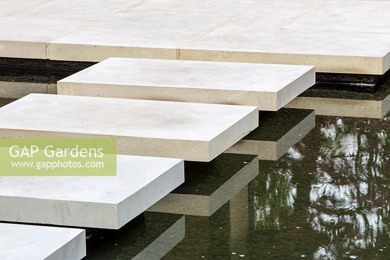 Floating stone stepping stones leading to a stone patio. A Japanese Reflection garden, RHS Malvern Spring Festival, 2016. Design: Peter Dowle and Richard Jasper - Howle Hill Nursery
