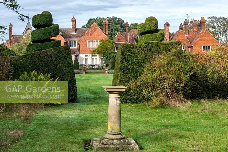 View between yew hedging and topiary to large country house beyond 