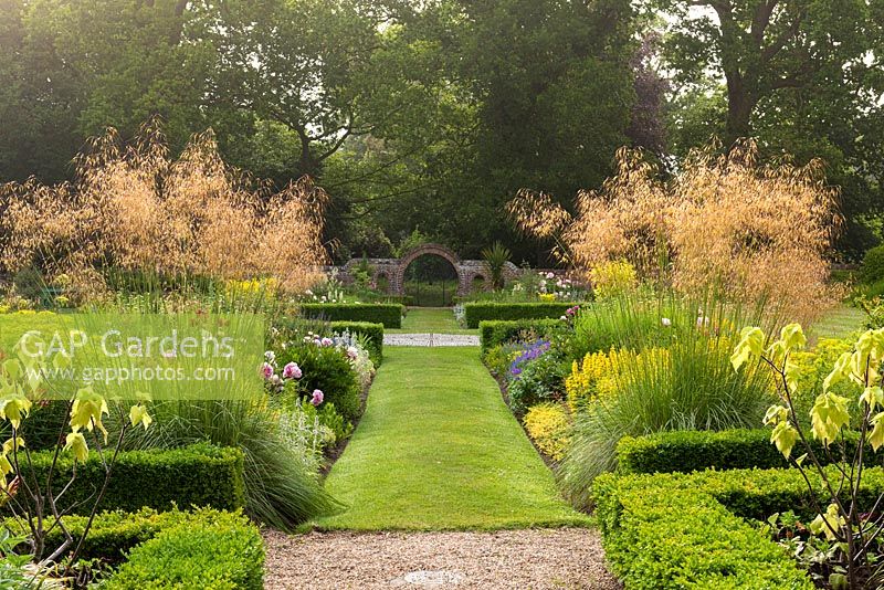 View along grass path between large summer borders with Stipa gigantea