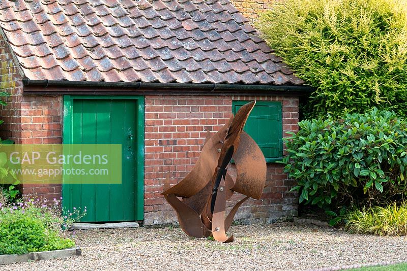 A contemporary sculpture in front of an old potting shed