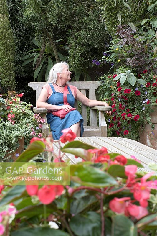 Woman sitting in seating area of garden with planted containers