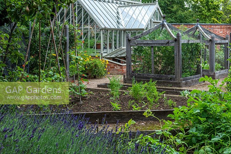 A formal kitchen garden with bespoke oak cloches to protect vulnerable crops, raised beds for runner beans and carrots, and a greenhouse.