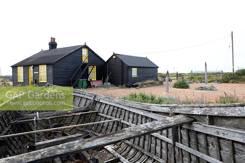 Cottage and garden on a shingle beach, old boat hull in foreground