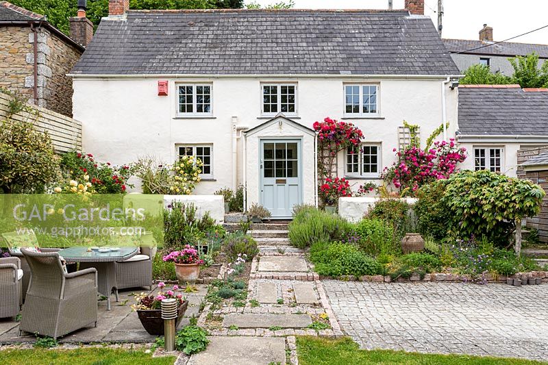 A front garden with seating and Rosa - Climbing Rose - around cottage