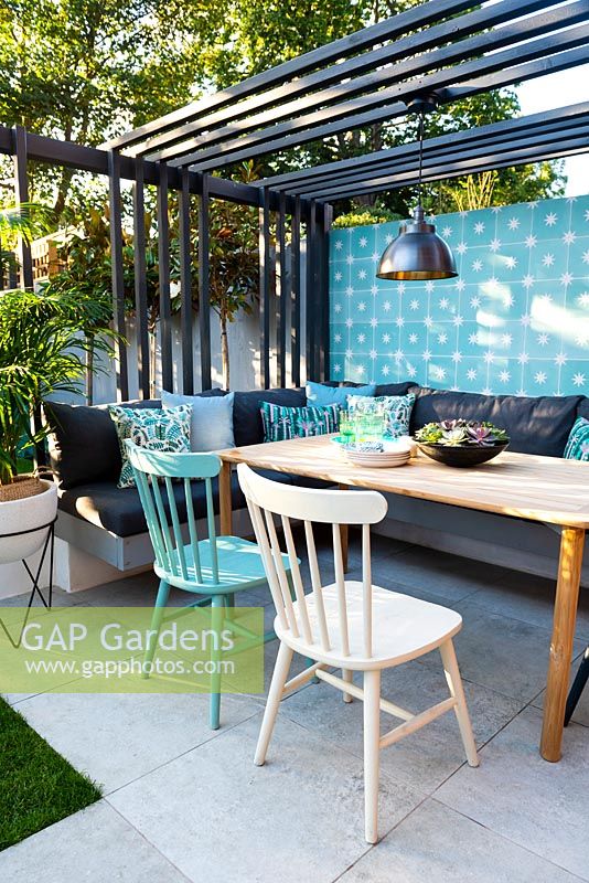 Dining area with colourful wall, chairs, modern pergola and industrial style lamp.