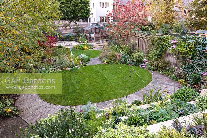 Low maintenance city garden overview of oval lawn with decking edging