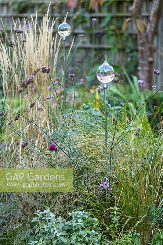 Low maintenance  city garden with grasses and glass garden ornaments
