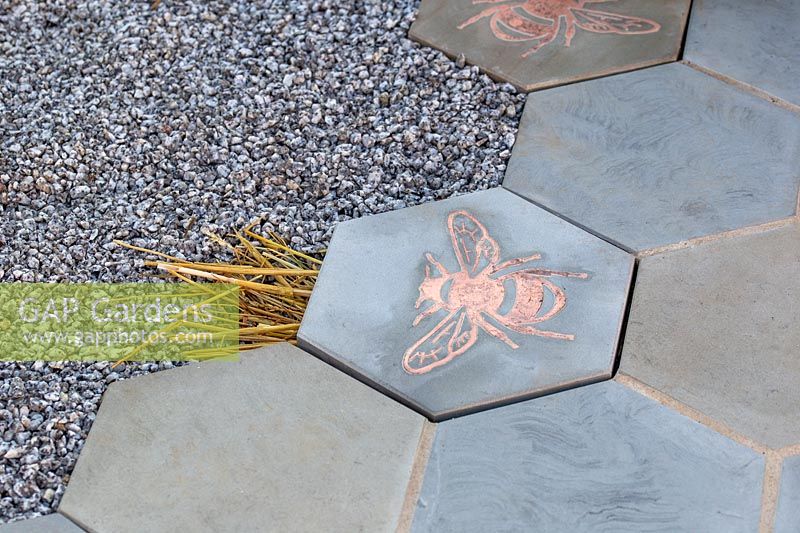 Hexagonal paving incorporating bee-printed tiles to identify entrances to underground bumblebee nests. The Urban Pollinator garden- Hampton Court Flower Festival 2019 