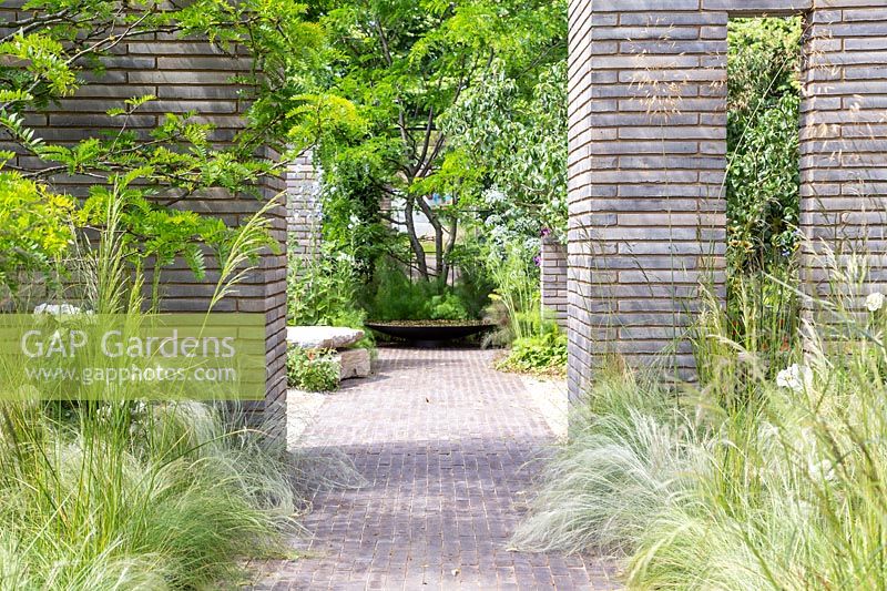 Garden with ornamental grasses divided by Belgium brick paver columns and walls. RHS Sanctuary Garden - Hampton Court Flower Festival 2019 